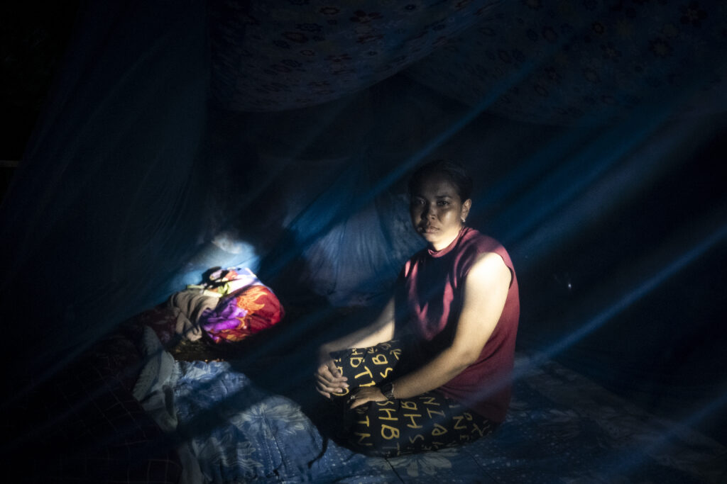 A woman sits under a mosquito net set up in her tent, in a camp set up at a night market park outside Sisophon town in Cambodia’s Banteay Meanchey province on December 16, 2025. (Roun Ry/Mekong Independent)