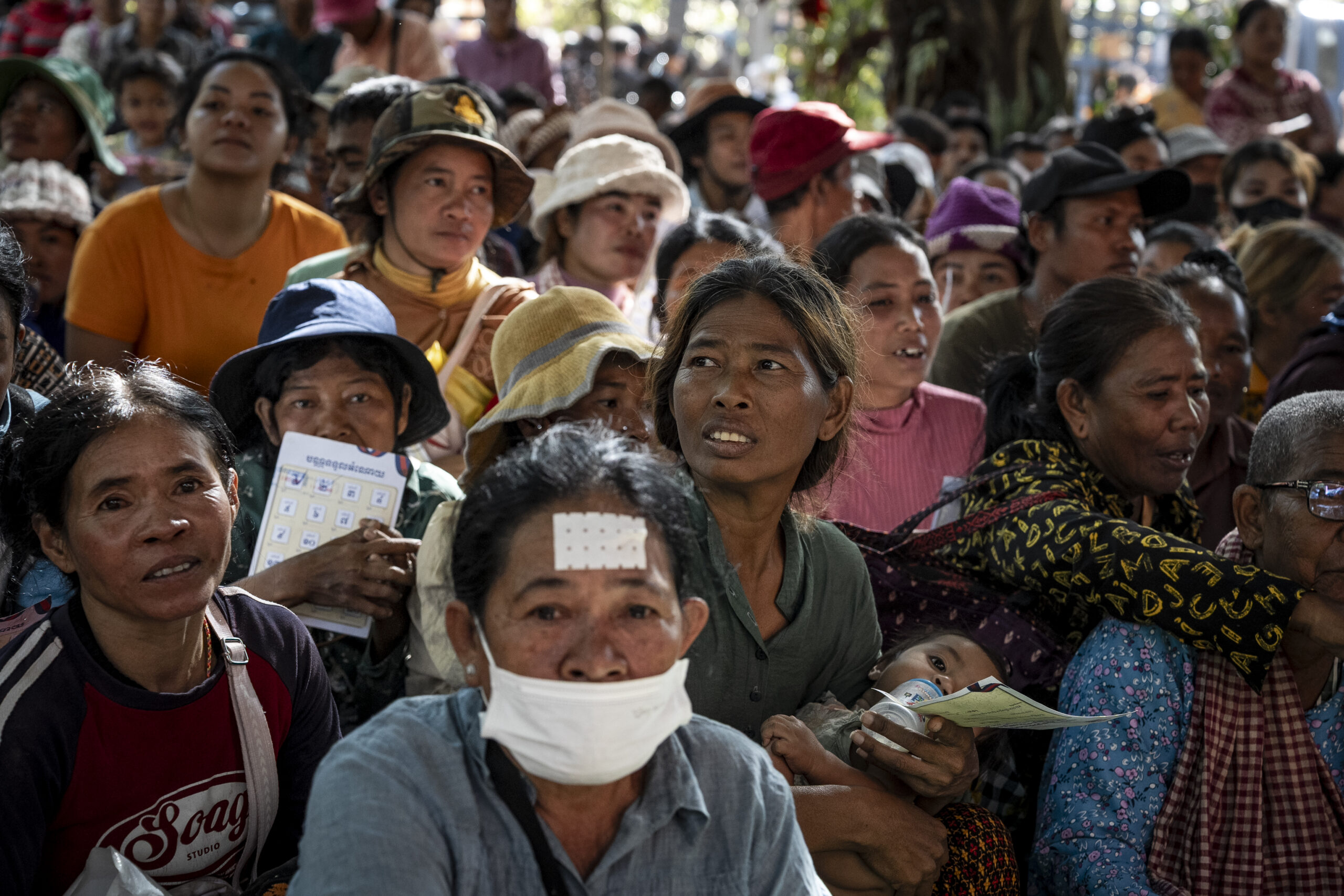 Civilians hold tickets representing their families' place in the queue and wait among thousands for their numbers to be called during a donation distribution at the displaced persons camp in the Chroy Neang Ngourn pagoda in Cambodia’s Siem Reap province on December 15, 2025. (Roun Ry/Mekong Independent)