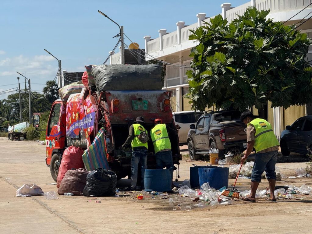 Waste collectors sweep and load trash into a garbage truck at a camp for internally displaced people at Khiev Moeung Ou Taki market in Battambang province's Thma Koul district on December 16, 2025. (Mech Dara/Mekong Independent)