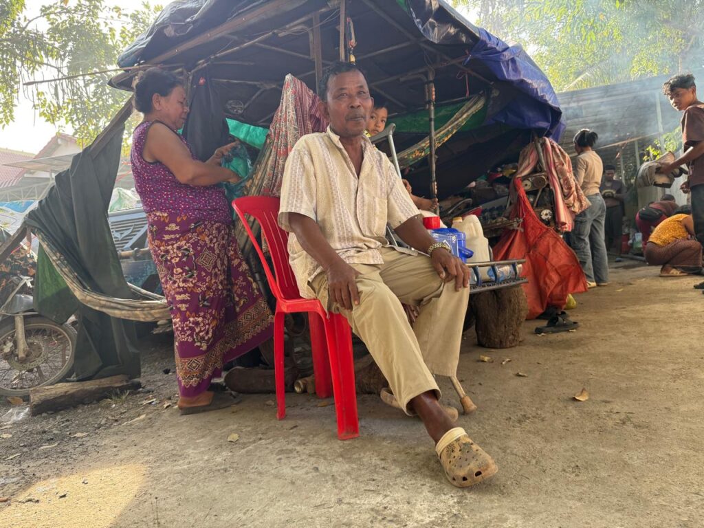 Lay Seak, 62, (left) and her husband in front of their campsite at the resettlement site in Khnah Romea pagoda in XXX province on December 16, 2025. (Mech Dara/Mekong Independent)