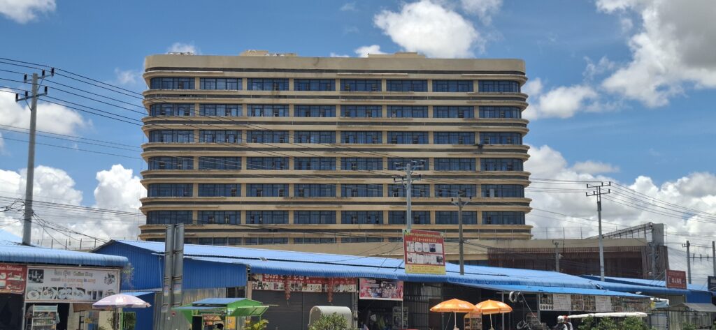A tower of Mango Park looms above a roadside market in Cambodia's Kampong Speu province on August 13, 2025. (Danielle Keeton-Olsen/Mekong Independent)
