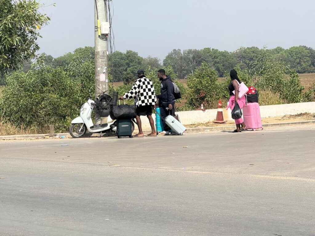 Three foreign workers stack bags onto a motorbike outside the Meun Chey Commercial Park compound in Cambodia's Prey Veng province on January 18, 2026. (Mech Dara/Mekong Independent) 