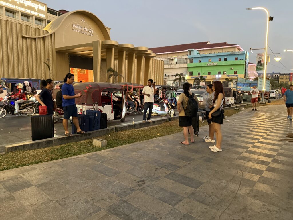 Foreigners stand with luggage in front of a beachside compound called Huangguan Chang Long Resort Hotel in Cambodia's Sihanoukville city, reportedly leaving ahead of a raid, on January 14, 2026. (Mech Dara/Mekong Independent)