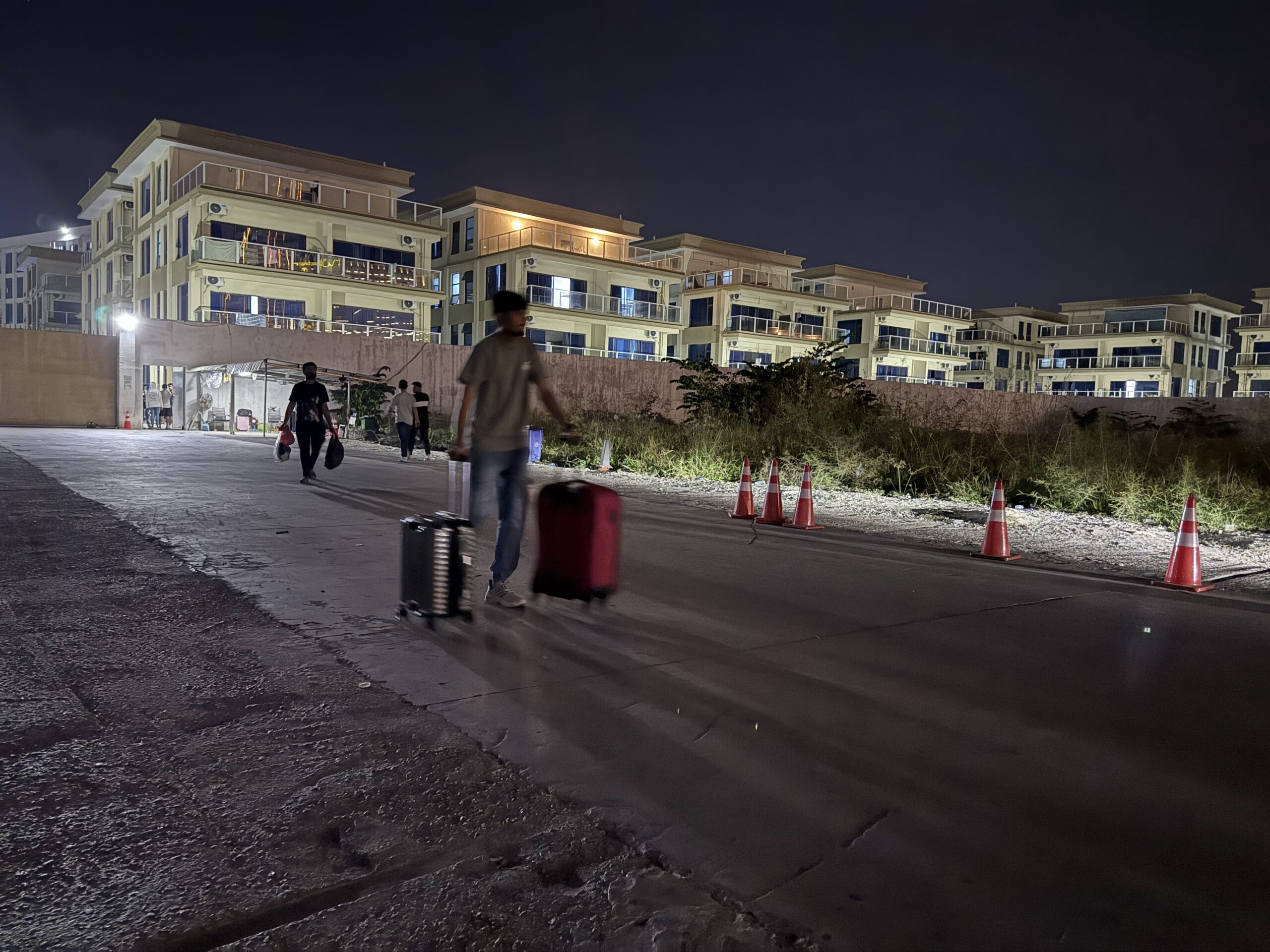 A worker pulls two rolling suitcases out of Jin Bei 6 compound in Cambodia's Sihanoukville city on January 14, 2026. (Mech Dara/Mekong Independent/Creative Commons)