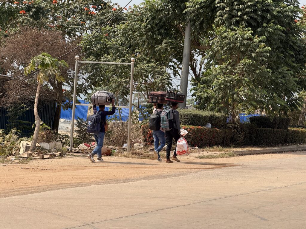 Foreigners carry suitcases on their heads and backpacks while walking through the Dara Sakor Resort in Cambodia's Koh Kong province on January 26, 2026. (Mech Dara/Mekong Independent)