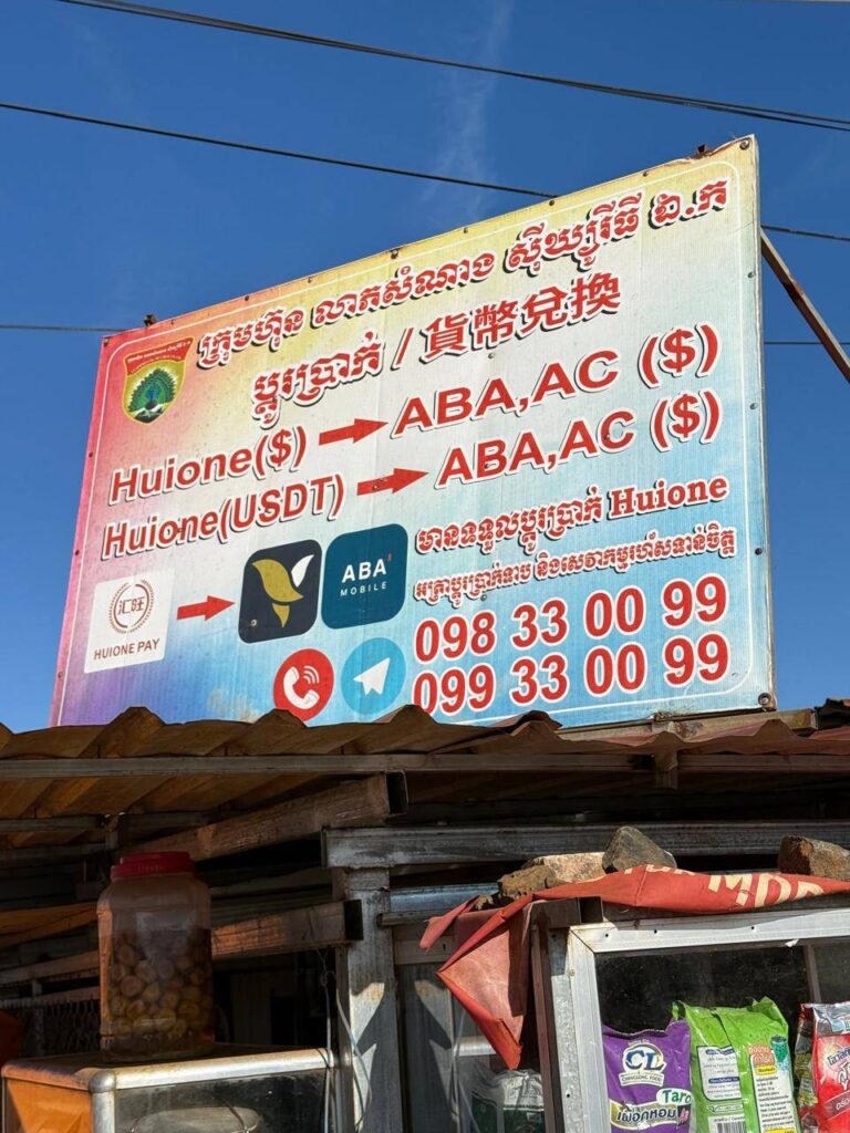 A billboard advertising money transfers between Huione and local banks ABA and Acleda outside the Mondulkiri Vegetable & Fruit Wholesale Market in Mondulkiri's  Dak Dam commune on December 28, 2025. (Mech Dara/Mekong Independent/Creative Commons)