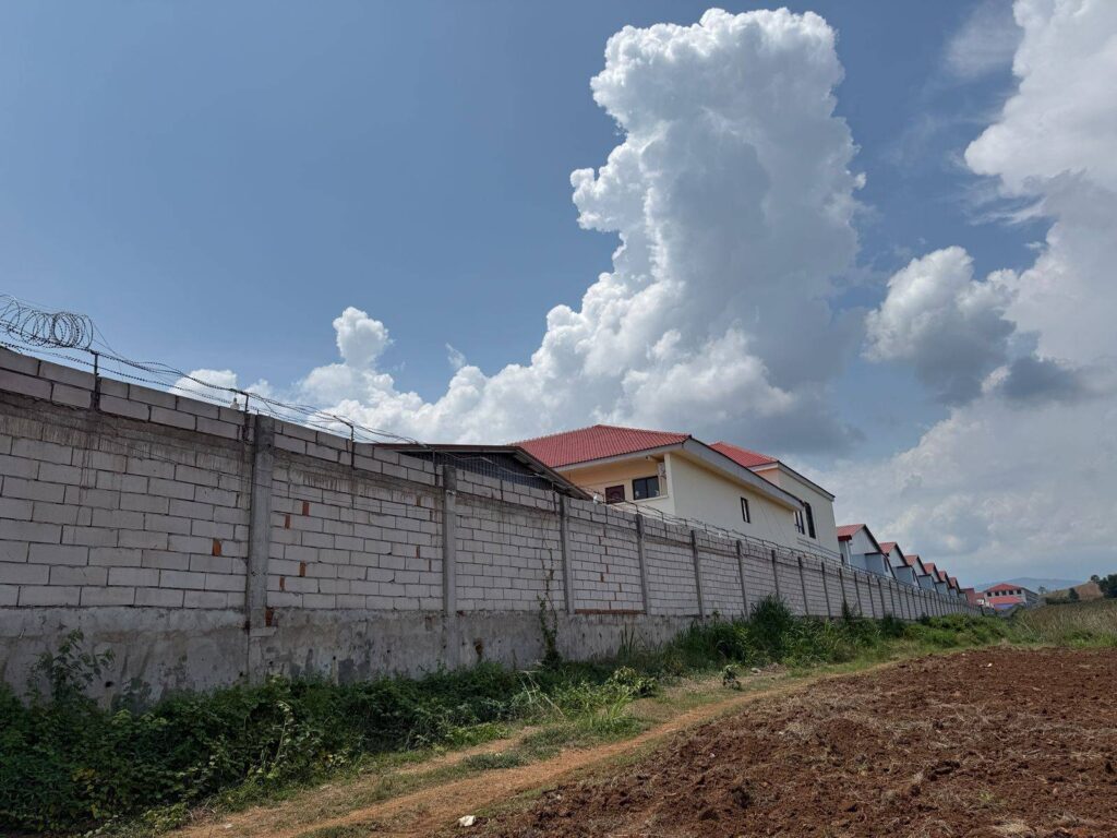 A row of housing structures is visible over the concrete gate of Cangxinlong Food (Cambodia) complex in Pailin province's Stung Kach commune on May 7, 2026. (Mech Dara/Mekong Independent/Creative Commons)