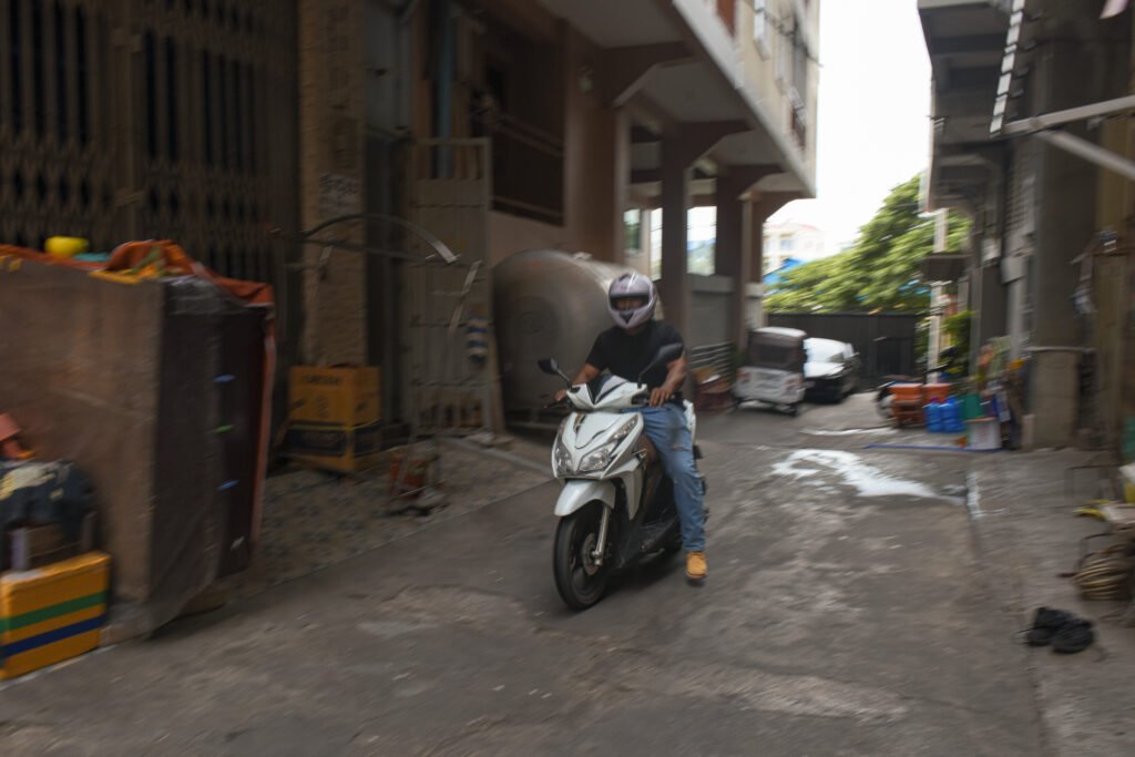 Pheap Rom rides his motorbike through an alley in Phnom Penh on July 27, 2026. (Len Leng/Mekong Independent/Creative Commons)