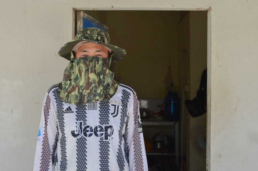 Orn Vannak, 42, just started working at a subcontracted factory after years of working with seniority pay and benefits in Poipet. He showed reporters the hat and mask he wears every day to avoid fabric debris in the factory at his rented room in Phnom Penh on August 23, 2026. (Danielle Keeton-Olsen/Mekong Independent)