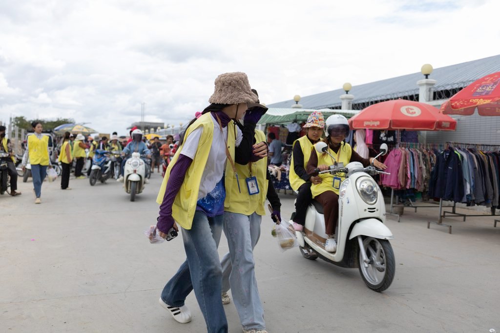 Garment workers walk and drive together out of a garment factory at the end of a shift in Phnom Penh on DATE. (Mech Choulay/Mekong Independent)