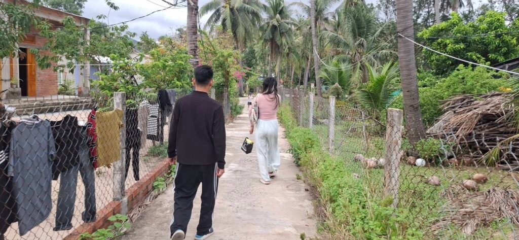 Học, Thư and their son walk between houses in a village in Central Viet Nam on September 19, 2026. (Danielle Keeton-Olsen/Mekong Independent)